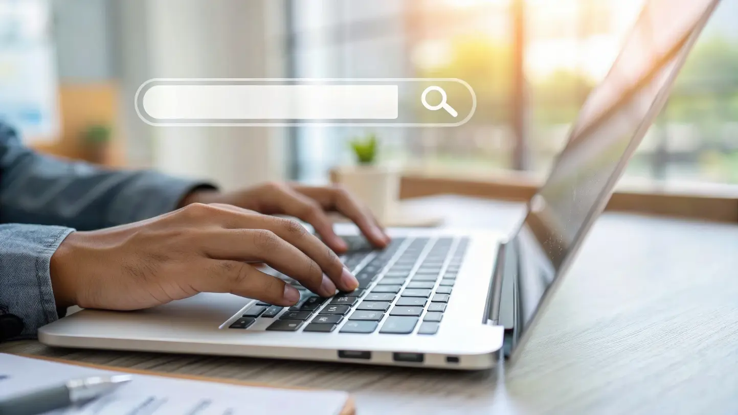 Person typing on a laptop with a search bar overlay, researching why their business is not showing up on Google Search