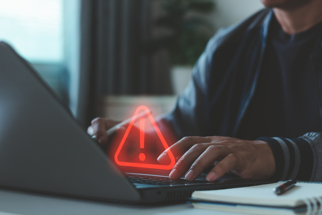 Red warning icon over a laptop symbolizing shadow IT risks in business technology