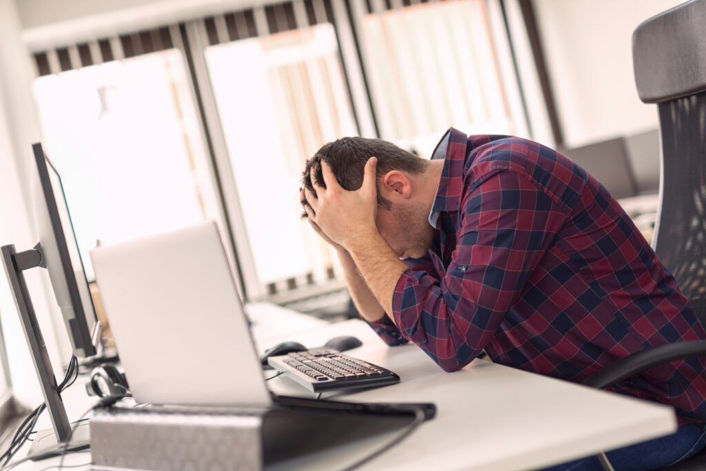 Stressed employee holding head in hands, illustrating common IT frustrations at work