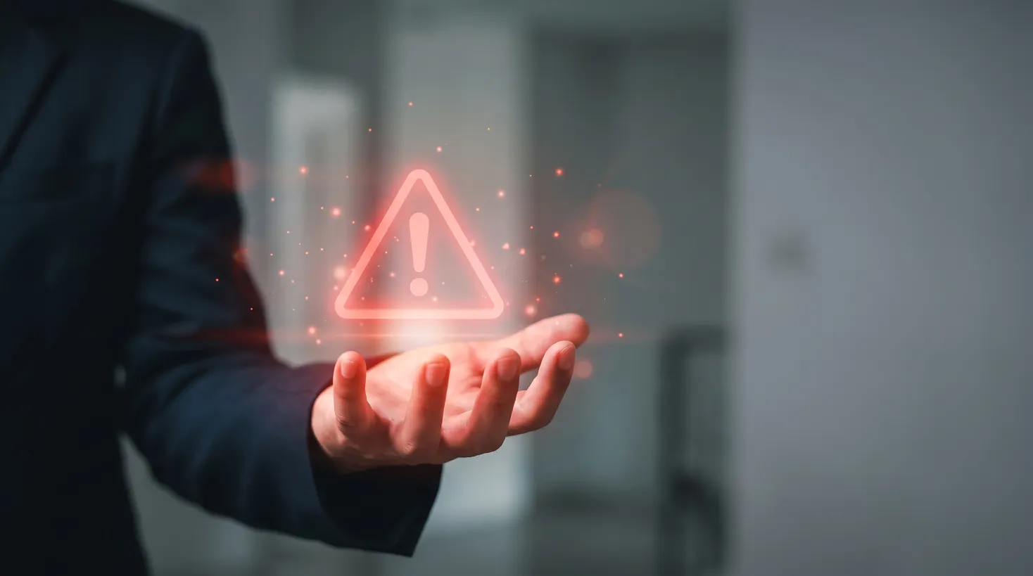 Businessman holding a digital warning icon, representing the risks reactive IT poses in the proactive IT vs reactive IT comparison